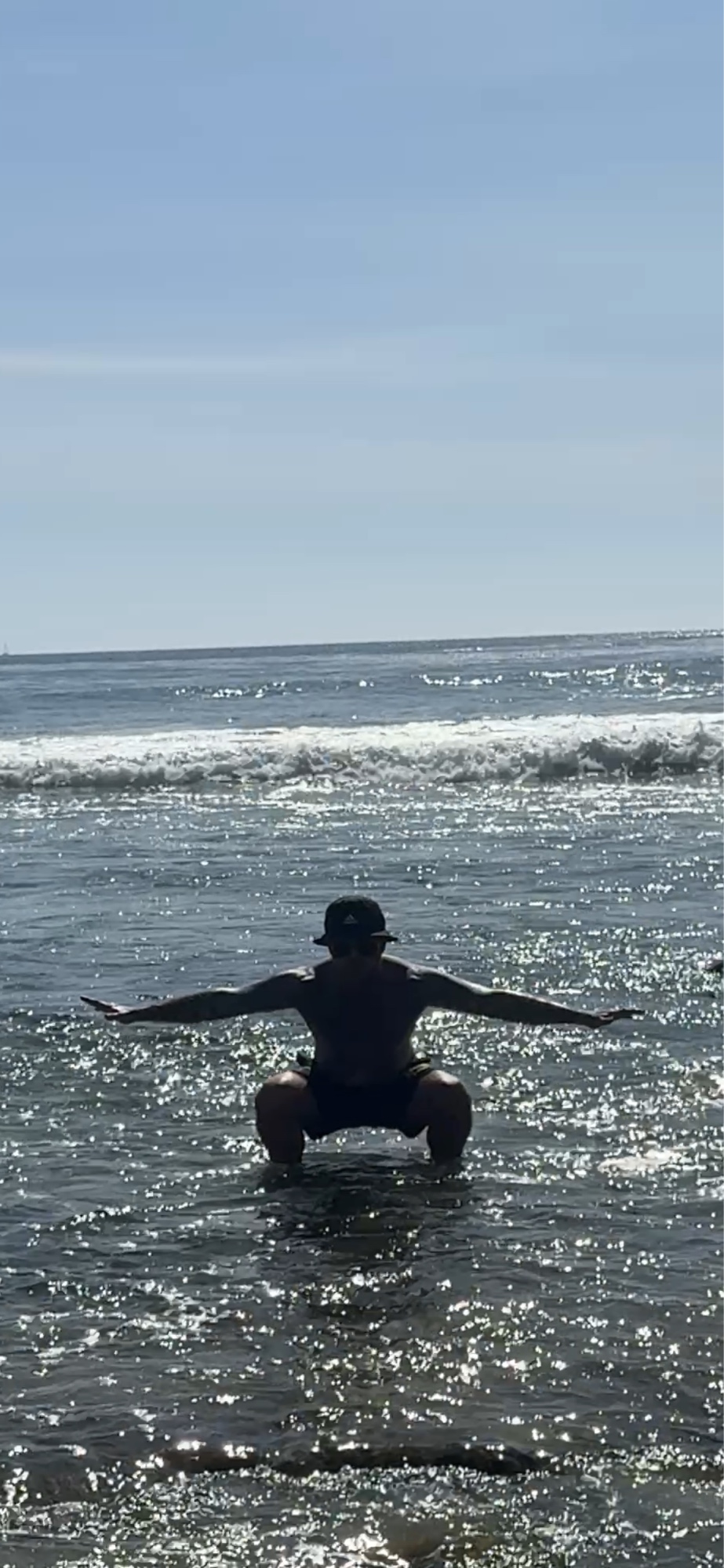 Shaun Anderson silhouetted practicing Korean breathwork at Laguna Beach, low squat stance